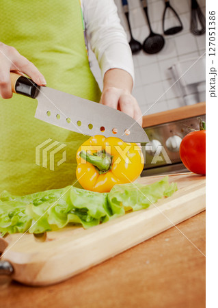 Woman chopping fresh yellow bell pepper on cutting board... 127051386