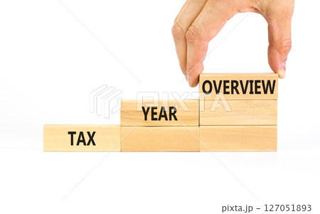 Tax year overview symbol. Concept words Tax year overview on beautiful wooden blocks. Beautiful white table white background. Businessman hand. Business tax year overview concept. Copy space. Tax year overview symbol. Concept words Tax year overview on beautiful wooden blocks. Beautiful white table white background. Businessman hand. Business tax year overview concept. Copy space. 127051893