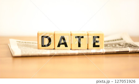 Date symbol. Concept word Date on beautiful wooden blocks on newspaper. Beautiful wooden table white background. Business and date concept. Copy space. Date symbol. Concept word Date on beautiful wooden blocks on newspaper. Beautiful wooden table white background. Business and date concept. Copy space. 127051926