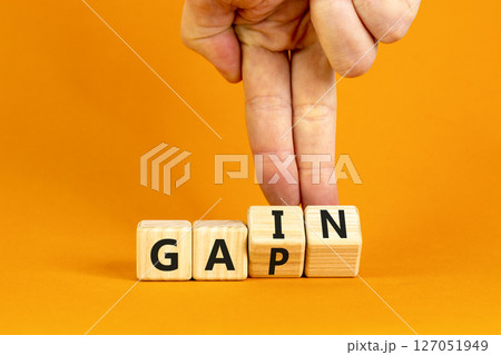Gain or gap symbol. Concept words Gain Gap on wooden block. Beautiful orange table orange background. Businessman hand. Business gain or gap concept. Copy space. Gain or gap symbol. Concept words Gain Gap on wooden block. Beautiful orange table orange background. Businessman hand. Business gain or gap concept. Copy space. 127051949