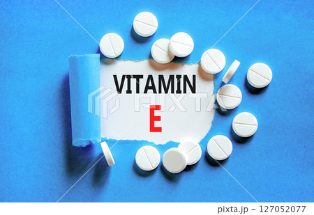 Vitamin E tocopherols symbol. Concept words Vitamin E on beautiful white paper. White pills tablets. Beautiful blue background. Medical healthy lifestyle Vitamin E tocopherols concept. 127052077