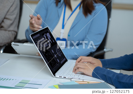 Business team doing paperwork, sitting at cafe on conference. Focused business team learning financial graphs, working on corporate project at briefing meeting. 127052175