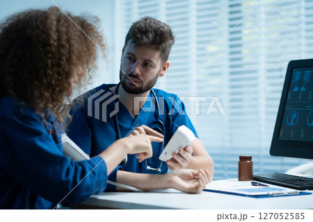 doctor checking woman blood pressure at clinic and filling patient history. 127052585