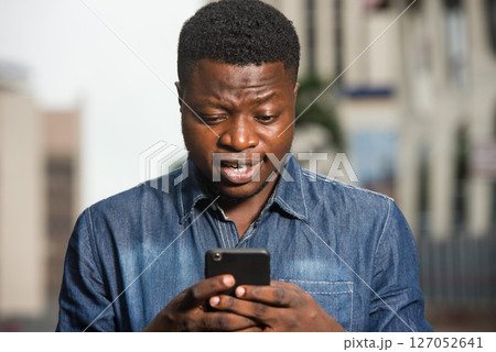 close-up of young man with mobile phone, happy. 127052641