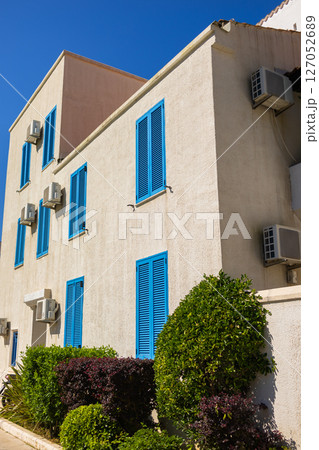 Facade with closed blue shutters. Mediterranean architecture, sunny climate, and summer lifestyle in coastal residential buildings Facade with closed blue shutters. Mediterranean architecture, sunny climate, and summer lifestyle in coastal residential buildings 127052689