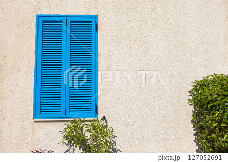 Blue shutter on beige wall. Mediterranean architecture, summer aesthetic, and coastal urban design with natural elements. 127052691