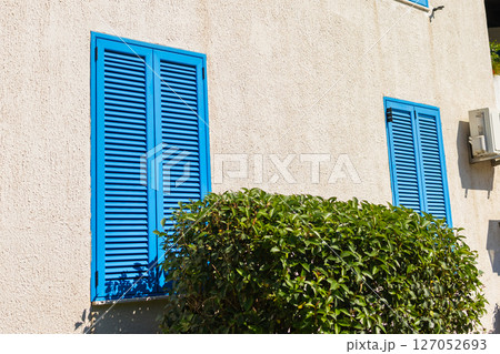 Facade with closed blue shutters. Mediterranean architecture, sunny climate, and summer lifestyle in coastal residential buildings 127052693