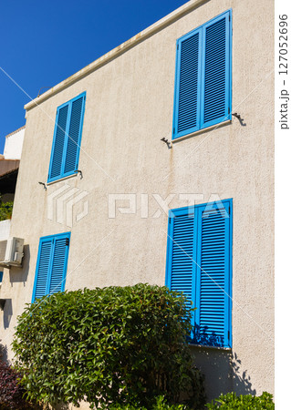 Facade with closed blue shutters. Mediterranean architecture, sunny climate, and summer lifestyle in coastal residential buildings 127052696