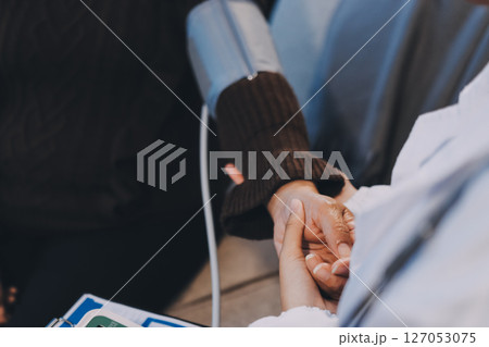 Doctor using Blood pressure monitor and stethoscope checking measuring arterial blood pressure on arm to a patient in the hospital, healthcare and medical concept 127053075