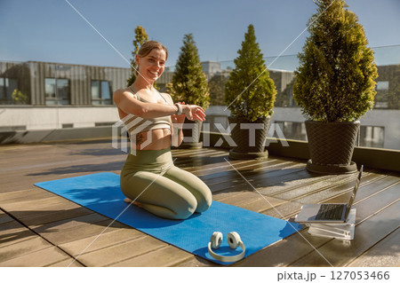 A woman is practicing yoga outdoors on a beautiful and sunny rooftop, embracing nature and serenity 127053466