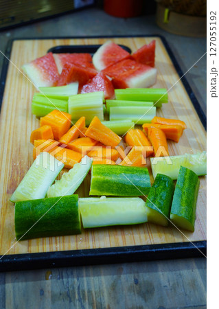Various cut vegetables and watermelon pieces are arranged on a wooden cutting board 127055192