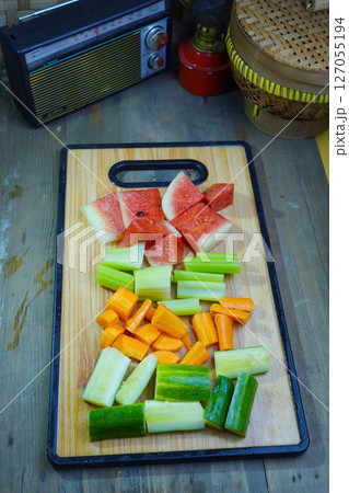 Various cut vegetables and watermelon pieces are arranged on a wooden cutting board Various cut vegetables and watermelon pieces are arranged on a wooden cutting board 127055194
