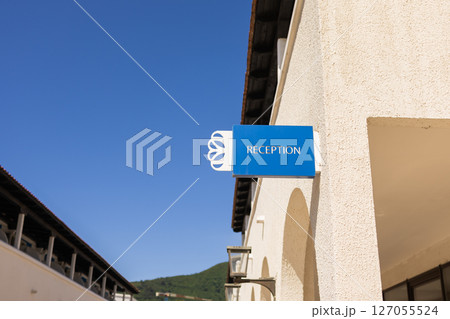 Reception sign on hotel wall. Tourist services, summer accommodation, and welcoming architecture in coastal destination. 127055524