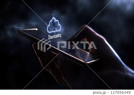 Close Up of Hand Holding Smartphone Displaying Downloading Icon Against Dark Background 127056349