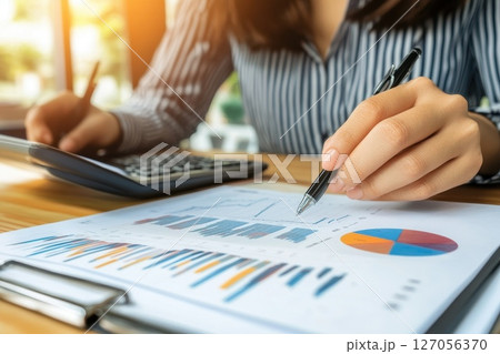 Business Executive Working in a Sleek Modern Office with Reports and Calculator 127056370