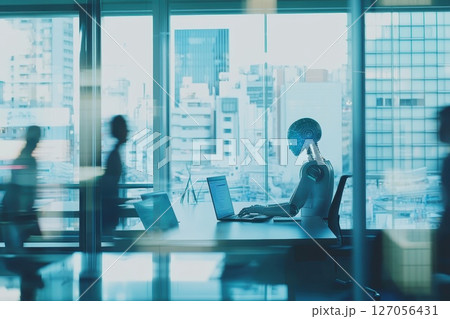 A robot is sitting at a desk in front of a laptop A robot is sitting at a desk in front of a laptop 127056431