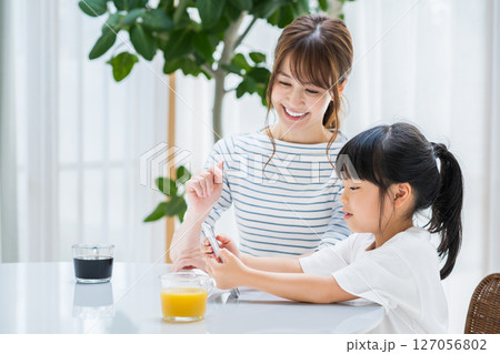 リビングでタブレットを一緒に見る親子 127056802