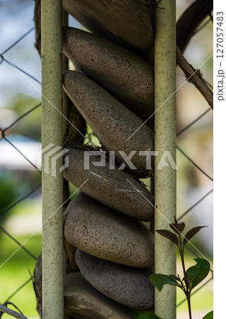A fence made of stones. A column of round stones 127057483