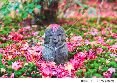 Jizo smiling Buddha by red autumn maple leaf at Enkoji garden, Kyoto Jizo smiling Buddha by red autumn maple leaf at Enkoji garden, Kyoto 127058076