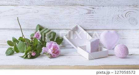 Spa still life with soap and pink rose flower on white wooden background. 127058572