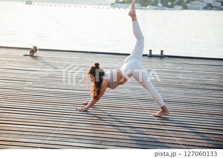 Athletic woman doing gymnastics yoga asana on the beach by the sea 127060133