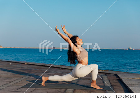 Athletic woman doing gymnastics yoga asana on the beach by the sea Athletic woman doing gymnastics yoga asana on the beach by the sea 127060141