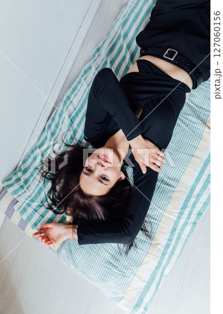 Slim fashionable woman in black clothes lying on mattress 127060156
