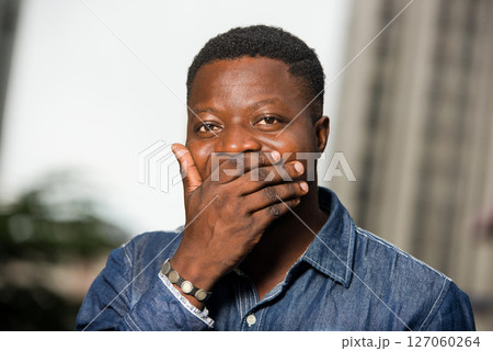 portrait of young man laughing and covering his mouth with the hand portrait of young man laughing and covering his mouth with the hand 127060264