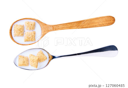 corn pillows with milk in a metal spoon isolated on white background, top view. 127060485