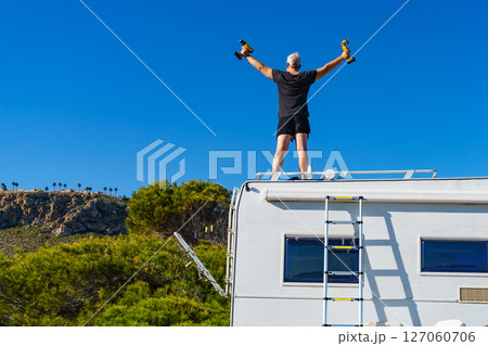 Man on roof of caravan. Repair motor home. 127060706