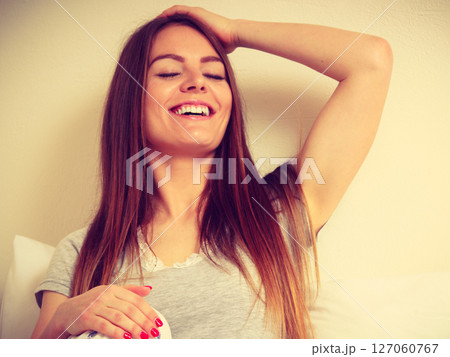 Happy sitting woman with one hand raised 127060767