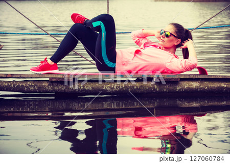 Girl training in sporty clothes on lake shore 127060784
