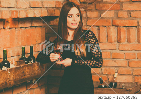 Woman tasting wine in rural cottage interior 127060865