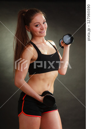 Fit woman exercising with dumbbells. 127060890