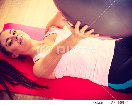 Young lady lying on the mat with fit ball. 127060954