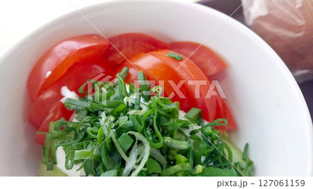 Fresh Salad With Tomato, Onions, and Green Herbs Served in a Bowl at a Sunny Outdoor Cafe 127061159