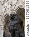 Bronze statue of a lion in front of the beautiful ancient building of the Hungarian Parliament in neo-gothic style 127061386
