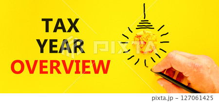 Tax year overview symbol. Concept words Tax year overview on beautiful yellow paper. Beautiful yellow background. Businessman hand. Light bulb icon. Business tax year overview concept. Copy space. 127061425