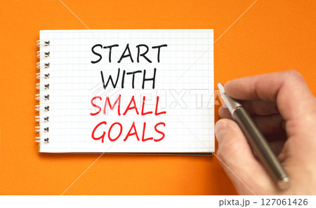 Start with small goals symbol. Concept words phrase Start with small goals on beautiful white note. Businessman's hand. Beautiful orange background. Business Start with small goals concept. Copy space 127061426