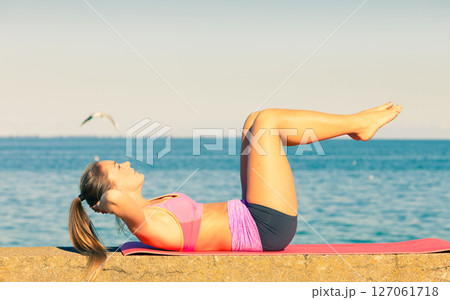 Woman doing sports exercises outdoors by seaside 127061718
