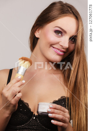Woman in lingerie applying loose powder with brush Woman in lingerie applying loose powder with brush 127061778