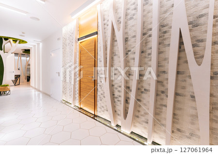 Empty corridor in modern beauty clinic featuring decorative brick tile wall, white curves and led lighting, creating welcoming and relaxing atmosphere, no people, nobody. Empty corridor in modern beauty clinic featuring decorative brick tile wall, white curves and led lighting, creating welcoming and relaxing atmosphere, no people, nobody. 127061964