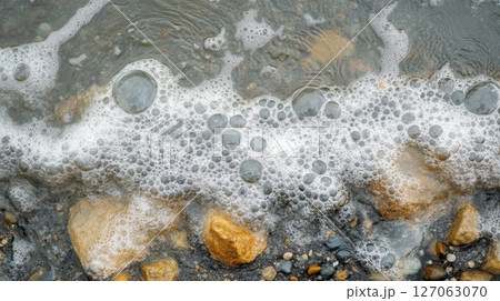 White Foam Bubbles on Water With Rocks and Gravel White Foam Bubbles on Water With Rocks and Gravel 127063070