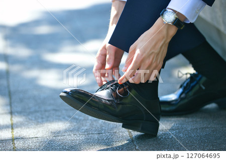 ビジネスシューズの靴紐を結ぶスーツの若い男性の足元 ビジネスシューズの靴紐を結ぶスーツの若い男性の足元 127064695