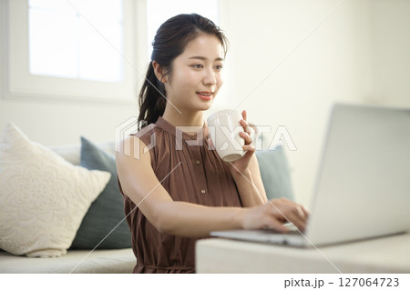 リビングでノートパソコンに向かう20代女性 リビングでノートパソコンに向かう20代女性 127064723