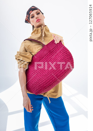 Beautiful woman holding fashionable red woven bag. Fashion and luxury accessories. Vertical photo. High quality photo 127065914