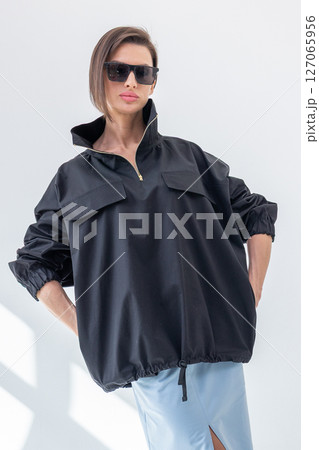 Elegant woman in black windbreaker jacket and light blue skirt on white background. Fashionable female style. Studio photography. Vertical photo. High quality photo Elegant woman in black windbreaker jacket and light blue skirt on white background. Fashionable female style. Studio photography. Vertical photo. High quality photo 127065956