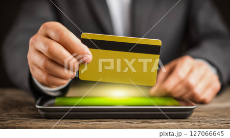 Businessman using credit card for online payment on tablet with glowing screen in modern office Businessman using credit card for online payment on tablet with glowing screen in modern office 127066645