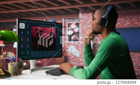 Black graphic designer working in loft with AI image generator software. Digital screen displaying visuals created through machine learning and cloud computing, generative AI. Camera B. 127068094