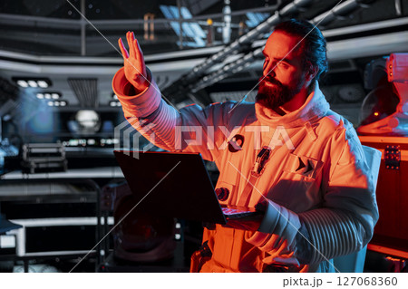 Spaceship crew member stressed by unknown hull breach causing alarm to sound. Worried cosmonaut reacts to system failure as radiation spike triggers emergency red lights inside orbital cockpit Spaceship crew member stressed by unknown hull breach causing alarm to sound. Worried cosmonaut reacts to system failure as radiation spike triggers emergency red lights inside orbital cockpit 127068360